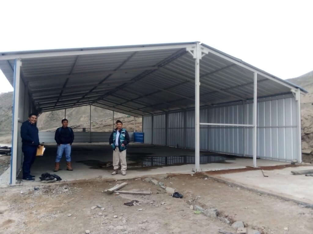 Smiling men stand inside the partially finished structure of the new church building under construction in Chancay.